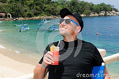 Young caucausian man enjoys coctail at ocean resort during summ Stock Photo