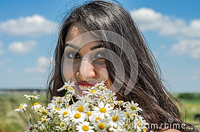 Young charming brunette girl with a bouquet of white field chamomiles on a summer sunny day Stock Photo