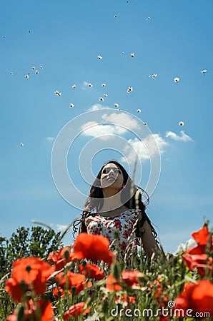 A young charming girl in a chamomile poppy field throws flowers of daisies on a bright sunny day Stock Photo