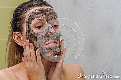 Young charming girl makes a black charcoal mask on her face Stock Photo