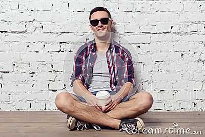 Young charming hipster sitting against the wall Stock Photo