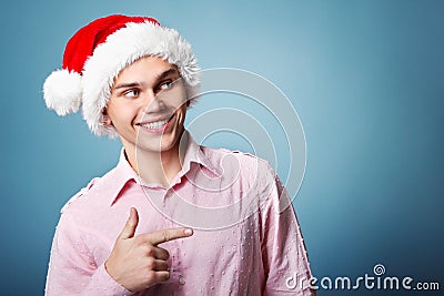 Young cheerful christmas man with santa`s hat point with hand le Stock Photo