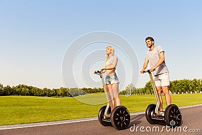 Young cheerful couple in love driving segways and smiling in park Stock Photo