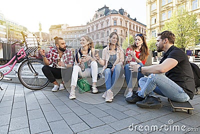 Five best friends have a gathering in the city street drinking take away coffee to go Stock Photo