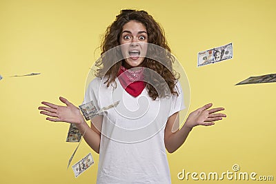 Young cheerful woman wins a lots of cash, over flying cash and yellow background Stock Photo