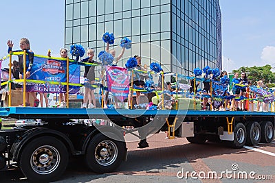 Young cheerleaders riding on truck at parade Editorial Stock Photo