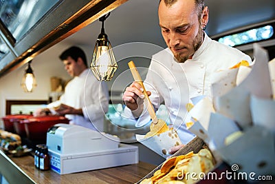Young chef serving barbecue potatoes in a food truck. Stock Photo