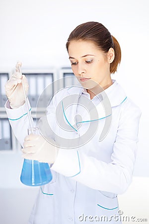 Young chemical female researcher with vials and flasks makes some experiments in laboratory Stock Photo