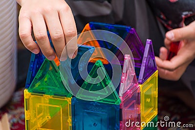 Young child building geometric magnetic shapes into a creative building at home indoors for education, problem solving, fun, Editorial Stock Photo