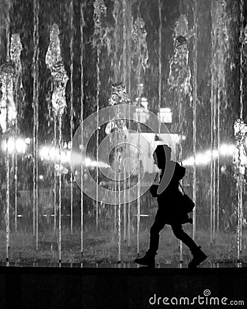 Young child girl walking the fountain border. Stylized as black and white silhouette Stock Photo