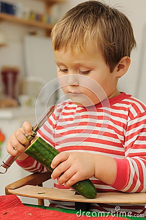 Young child peeling cucumber Stock Photo