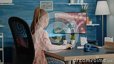 Young child playing action video games on computer at desk Stock Photo