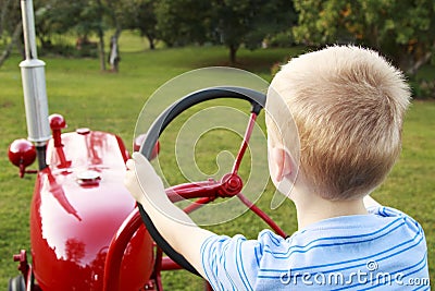 Young Child pretending to drive an old tractor Stock Photo