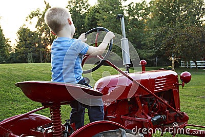 Young child pretending to drive a red tractor Stock Photo