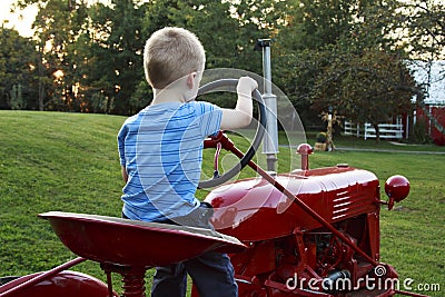 Young Child pretending to drive the red antique tractor Stock Photo