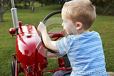 Young Child pretending to drive a red tractor Stock Photo