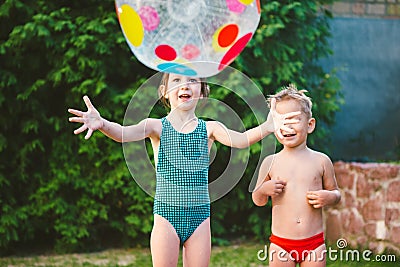 Young children siblings play large inflatable beach ball in courtyard of house in swimming pool. theme of heat and water games, Stock Photo