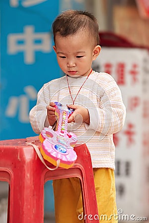 Young Chinese boy playing with his plastic toy, Guangzhou, China Editorial Stock Photo