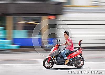 Young Chinese man on motorized scooter trushing through a street. Editorial Stock Photo