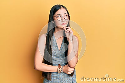 Young chinese woman wearing business dress and glasses thinking concentrated about doubt with finger on chin and looking up Editorial Stock Photo