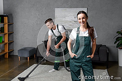 young cleaning company workers using vacuum cleaner and smiling Stock Photo