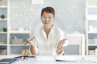 Young coach sitting at desk looking at camera and speaking, sharing experience, giving life advice Stock Photo
