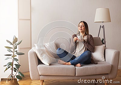 Young coffee lover sniffing hot drink at cozy home interior Stock Photo