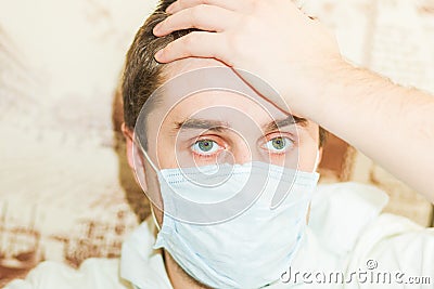 A young, cold man in a facial gauze bandage holds a sick head Stock Photo