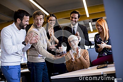 Young colleagues celebrate an older colleague`s birthday at the office and bring a cake Stock Photo