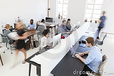 Young colleagues at computers in a busy open plan office Stock Photo