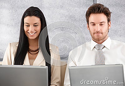 Young colleagues working on laptop smiling Stock Photo