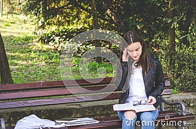 Young college or school girl feeling sick with strong headache pain or migraine attack while she sitting on the bench in the park Stock Photo