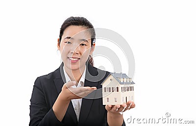 A young commercial house salesperson in front of a white background holds a small house model in his hand and introduces it to a c Stock Photo