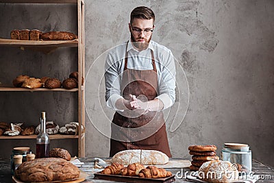 Young concentrated bearded man wearing glasses baker Stock Photo