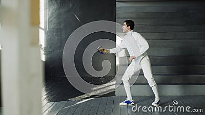 Young concentrated fencer man practice fencing exercises and training for Olympic games competition in studio indoors Stock Photo