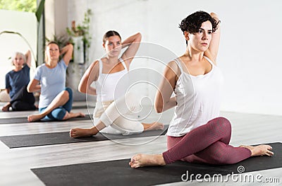 Young concentration girl maintaining mental and physical health attending group yoga class at studio, practicing Stock Photo