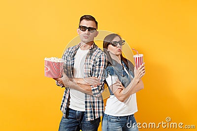 Young concerned couple woman man in 3d glasses watching movie film on date holding bucket of popcorn plastic cup of soda Stock Photo