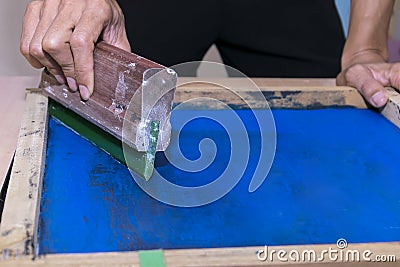 Young confident, experienced male working with squeegee on a small factory. Stock Photo