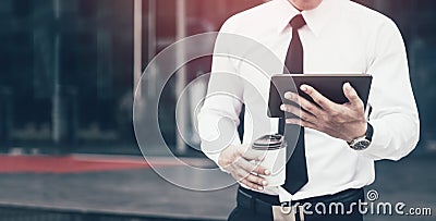 Young confident man economist holding digital tablet reading email or looking stock marketing with morning time. Stock Photo