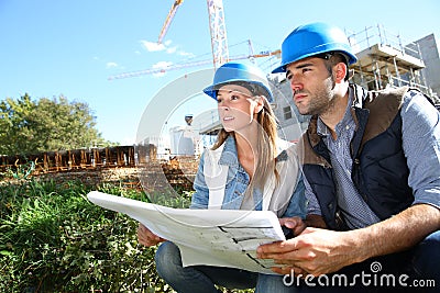 Young construction engineers with blueprint on site Stock Photo
