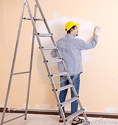 Young contractor sanding wall down with sandpaper Stock Photo