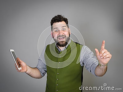 Young and cool austrian man with black hair and beard in traditional costume stands in front of a grey background Stock Photo