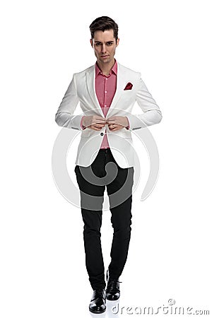 Young cool elegant man walking and buttoning his coat Stock Photo