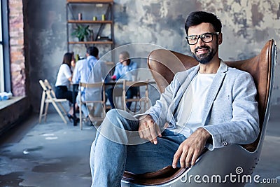 Young corporate executive sitting comfortably in a stylish chair in modern office. Stock Photo