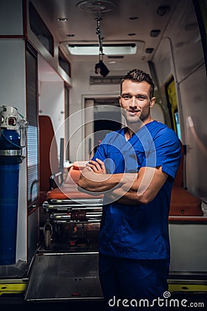 Young corpsman keeps a smile and stands over the ambulance car on the background Stock Photo