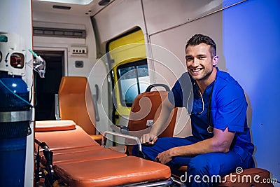 Young corpsman in blue uniform sits in the ambulance car and smiles Stock Photo