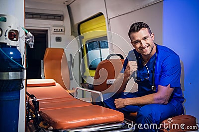 Young corpsman in uniform sits in the ambulance car and smiles Stock Photo