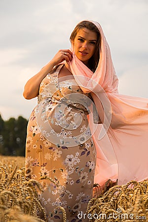 Young couple awaiting baby embrace the field Stock Photo