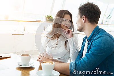 Young couple beautiful woman and handsome man drinking coffee in cafe looking at each other, love and tenderness concept Stock Photo