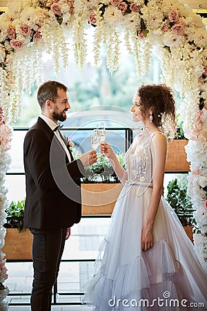 Young couple, bride and groom near arch. Wedding decor large wreath of flowers Stock Photo